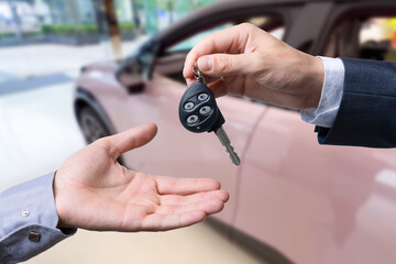 Close-up of dealer handing keys to new owners at a car show Automotive business Car sales Agreement Concept Men car salesman handing over new car keys.