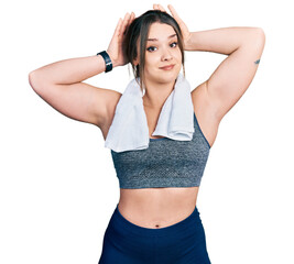 Young hispanic girl wearing sportswear and towel doing bunny ears gesture with hands palms looking...