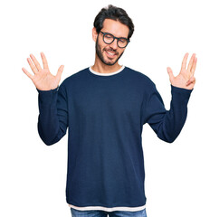 Young hispanic man wearing casual clothes and glasses showing and pointing up with fingers number nine while smiling confident and happy.