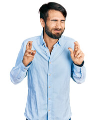 Hispanic man with blue eyes wearing business shirt gesturing finger crossed smiling with hope and eyes closed. luck and superstitious concept.