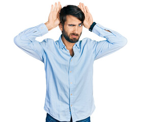 Hispanic man with blue eyes wearing business shirt doing bunny ears gesture with hands palms looking cynical and skeptical. easter rabbit concept.