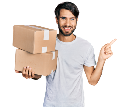 Hispanic man with blue eyes holding packages smiling happy pointing with hand and finger to the side - Powered by Adobe
