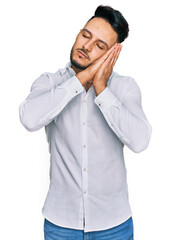 Young arab man wearing casual clothes sleeping tired dreaming and posing with hands together while smiling with closed eyes.