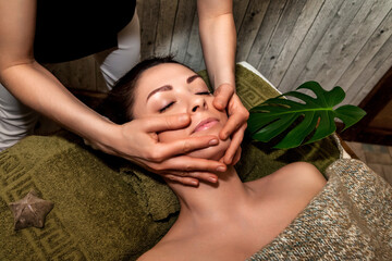 Obraz na płótnie Canvas Face massage therapy. Female hands massaging therapeutic massage face for lady lying in medical room in spa salon, indoors. Wellness, self skin care, healthy lifestyle concept. Copy ad text space