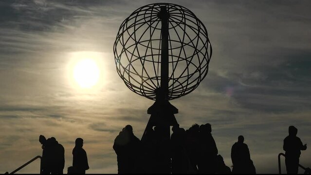 Silhouettes of people on the northern cape of Europe. Midnight sun on Nordkapp. North cape norway. Arctic norwegian sky. Travel, sunset, sunlight.