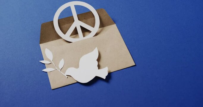 Close up of white dove with leaf, white peace sign, envelope and copy space on blue background