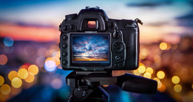Camera on the background of city lights and sunset. Concept on the topic of photography and photo technology.
