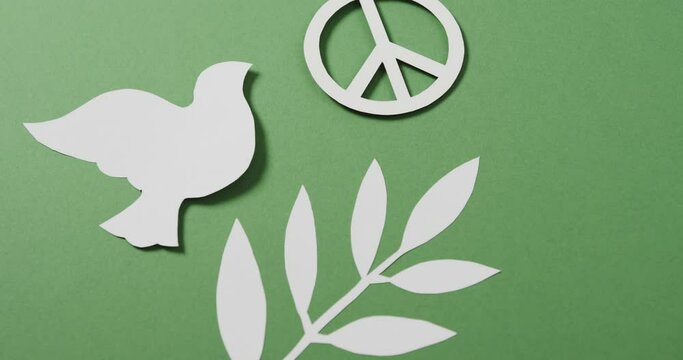 Close up of white dove with peace sign and leaf and copy space on green background