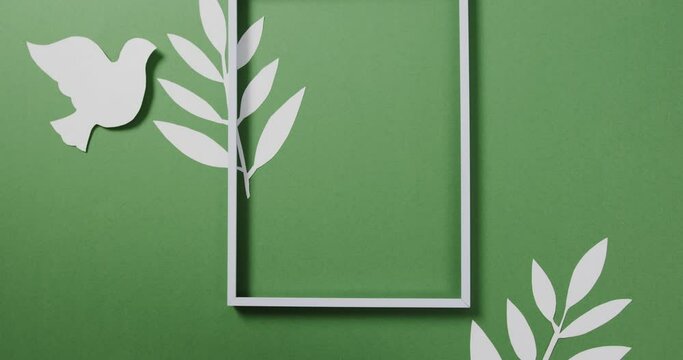 Close up of white dove with frame and leaves and copy space on green background