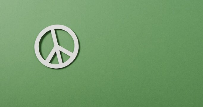 Close up of white peace sign and copy space on green background