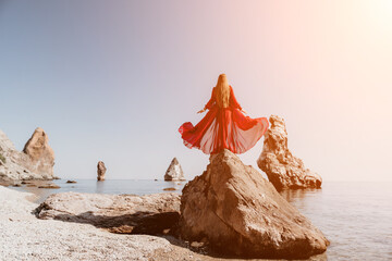 Woman travel sea. Young Happy woman in a long red dress posing on a beach near the sea on...
