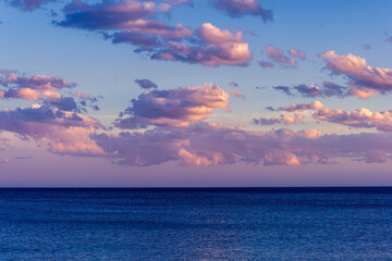 scenic blue seascape of sunset or sunrise above water with beautiful colorful evening clouds