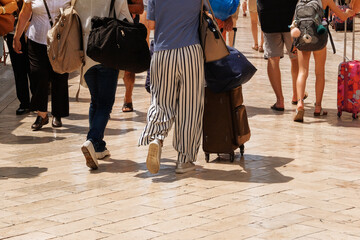 Travelers with suitcases is walking in the historical place in daylight. Passage between walls to the old town. Summer in Croatia.