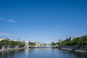 Fototapeta na wymiar Beautiful panoramic view from the Seine River to the bridge and the city landscape on a sunny summer day. Paris, France.