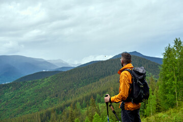 Hiker with trekking sticks enjoying mountains view  Resting and breathing. Activity and sport concept...