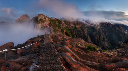 Landscape of sunrise in mountain over clouds in Madeira Island on Pico do Arieiro over steep cliffs and high peaks with  canyons  of the mountains in central Madeira. Portugal - obrazy, fototapety, plakaty