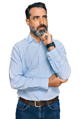Middle aged man with beard wearing business shirt with hand on chin thinking about question,...