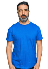 Fototapeta premium Middle aged man with beard wearing casual blue t shirt relaxed with serious expression on face. simple and natural looking at the camera.