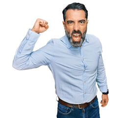 Middle aged man with beard wearing business shirt angry and mad raising fist frustrated and furious while shouting with anger. rage and aggressive concept.