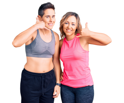 Couple of women wearing sportswear smiling doing phone gesture with hand and fingers like talking on the telephone. communicating concepts.