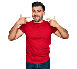 Hispanic man with beard wearing casual red t shirt smiling cheerful showing and pointing with fingers teeth and mouth. dental health concept.
