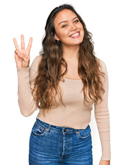Young hispanic girl wearing casual clothes showing and pointing up with fingers number three while smiling confident and happy.