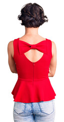 Beautiful young woman with short hair wearing casual style with sleeveless shirt standing backwards...