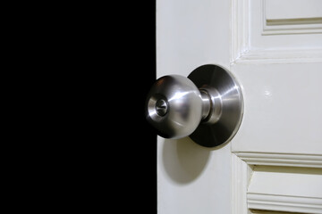 Stainless steel door knob or the handle on the wooden door In a brightly lit room. Darkroom background. concept of cleanliness and hygiene. Selective focus.
