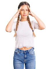 Beautiful caucasian woman with blonde hair wearing braids and white tshirt suffering from headache desperate and stressed because pain and migraine. hands on head.