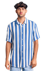 Young hispanic man wearing casual clothes puffing cheeks with funny face. mouth inflated with air, crazy expression.