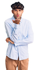 Young hispanic man wearing casual shirt looking at the camera blowing a kiss with hand on air being lovely and sexy. love expression.