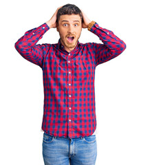 Fototapeta premium Handsome young man with bear wearing casual shirt crazy and scared with hands on head, afraid and surprised of shock with open mouth