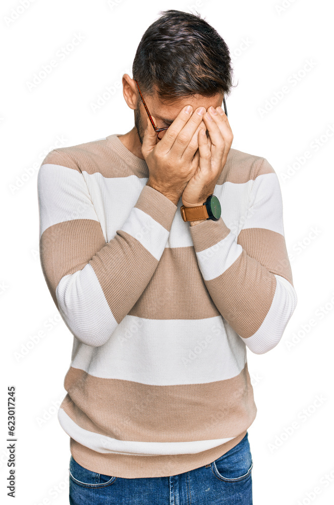 Poster handsome man with beard wearing casual clothes and glasses with sad expression covering face with ha