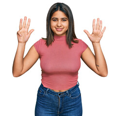 Young hispanic girl wearing casual t shirt showing and pointing up with fingers number nine while smiling confident and happy.