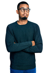 Young african american man wearing casual clothes and glasses smiling looking to the side and staring away thinking.