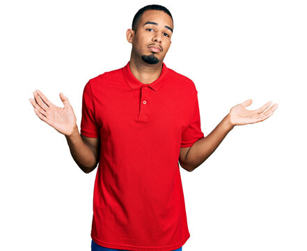 Young african american man wearing casual polo clueless and confused with open arms, no idea and doubtful face.