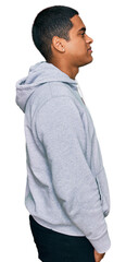 Young handsome hispanic man wearing casual sweatshirt looking to side, relax profile pose with natural face with confident smile.