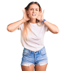 Beautiful caucasian woman wearing casual white tshirt trying to hear both hands on ear gesture, curious for gossip. hearing problem, deaf