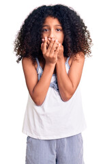 Fototapeta na wymiar African american child with curly hair wearing casual clothes shocked covering mouth with hands for mistake. secret concept.