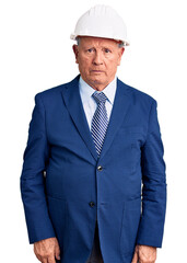 Senior handsome grey-haired man wearing suit and architect hardhat skeptic and nervous, frowning upset because of problem. negative person.