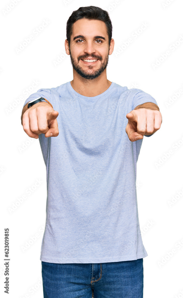 Wall mural Young hispanic man wearing casual clothes pointing to you and the camera with fingers, smiling positive and cheerful