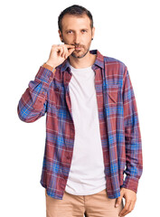 Young handsome man wearing casual clothes mouth and lips shut as zip with fingers. secret and...