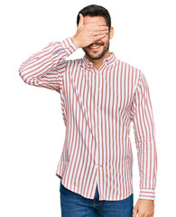 Fototapeta na wymiar Young hispanic man wearing business shirt smiling and laughing with hand on face covering eyes for surprise. blind concept.