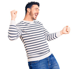Naklejka premium Young hispanic man wearing casual clothes dancing happy and cheerful, smiling moving casual and confident listening to music