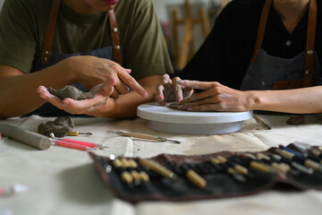 Cropped image of master ceramist teaches helping student creating plate handmade from clay in art workshop