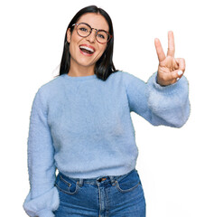 Young hispanic woman wearing casual clothes and glasses showing and pointing up with fingers number two while smiling confident and happy.