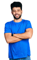 Young arab man with beard wearing casual blue t shirt happy face smiling with crossed arms looking at the camera. positive person.