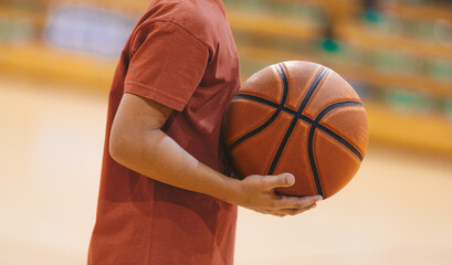 A basketball player holding a ball during a training session. Youth basketball team on practice...