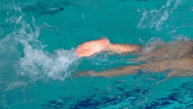 Freestyle legs kicking of the female swimmer in a pool.