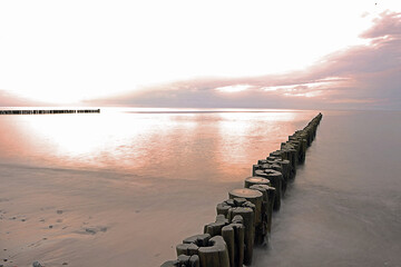 Wooden breakwater on the beach at sunset. Baltic Sea.